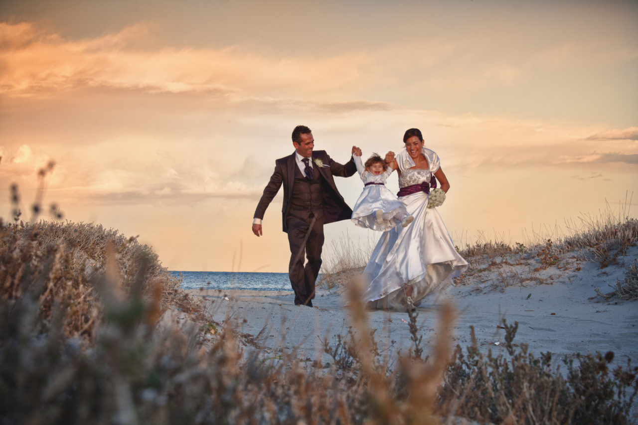 Famiglia felice tra le dune di una spiaggia olbiese. Fotografia scattata da Giuseppe Ortu esperto in matrimoni a Olbia.