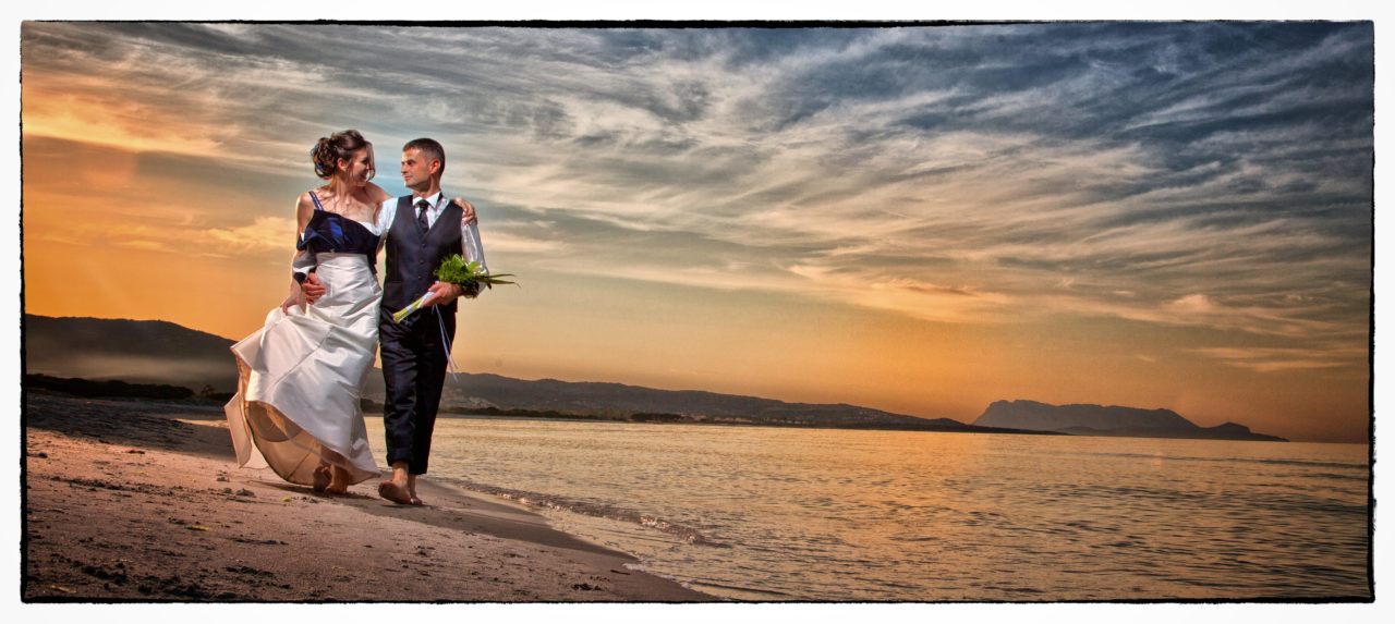 Sposi che passeggiano sul bagnasciuga. Foto scattata in stile Fine Art dal fotografo olbiese Giuseppe Ortu. Fotografo matrimoni Olbia.