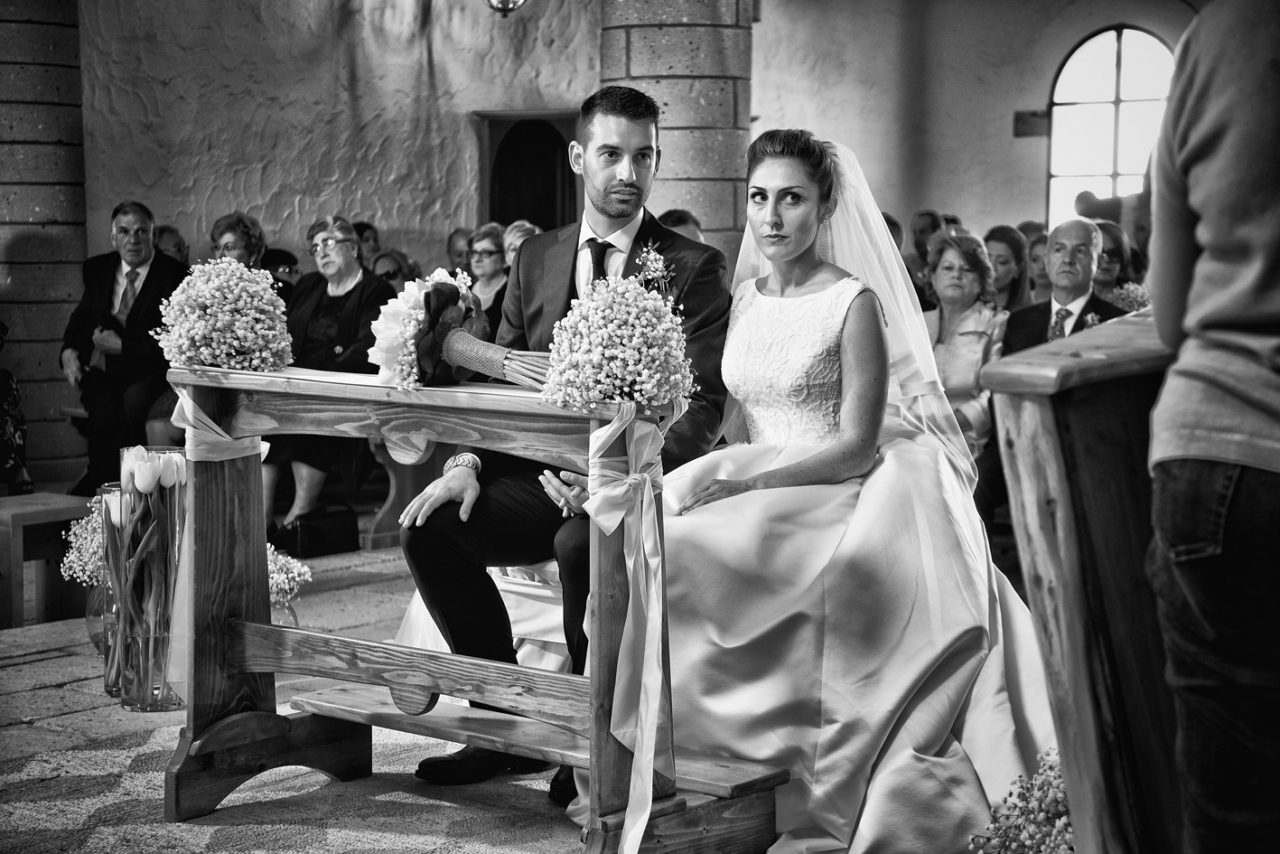Sposi in chiesa dietro il banchetto. Foto scattata da Giuseppe Ortu fotografo specializzato in matrimoni a Olbia