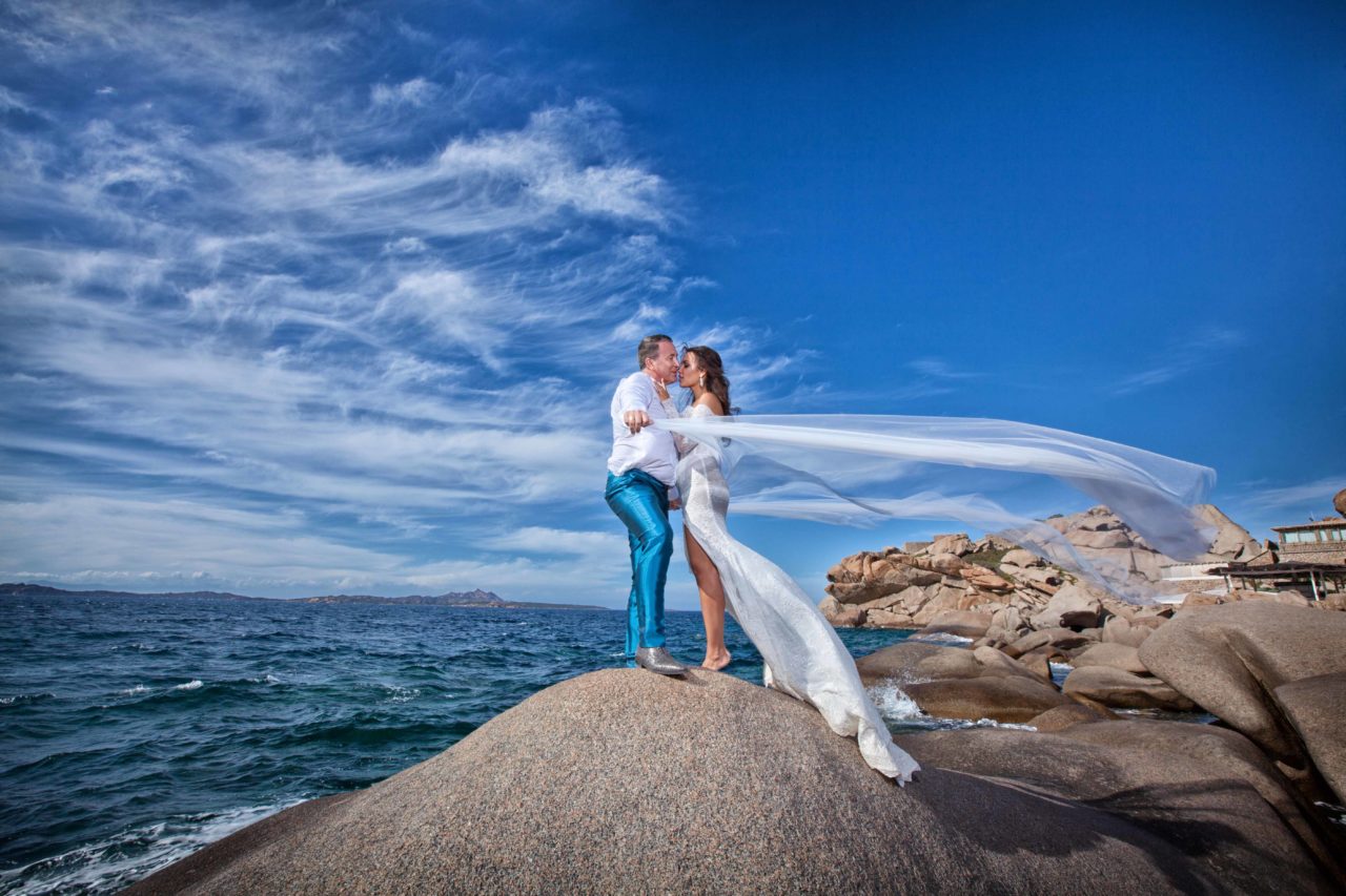Coppia di sposi che si bacia sugli scogli in riva al mare. Foto scattata da Giuseppe Ortu fotografo specializzato in matrimoni a Olbia.